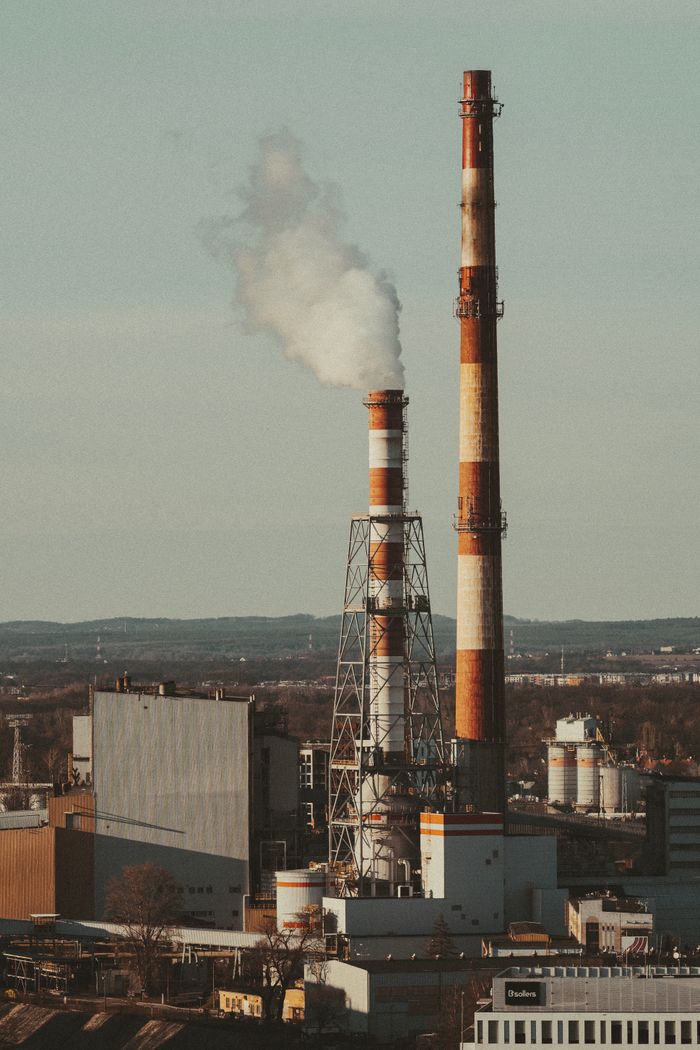 Outdoor view of industrial smokestacks releasing smoke, symbolizing environmental impact.